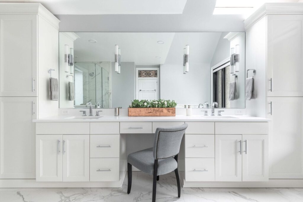 Bright bathroom with a custom mirror and modern white cabinetry.