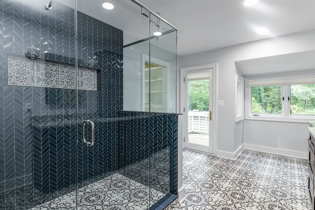 Luxury glass shower enclosure with a sleek design, featuring a modern navy tile wall and patterned floor.
