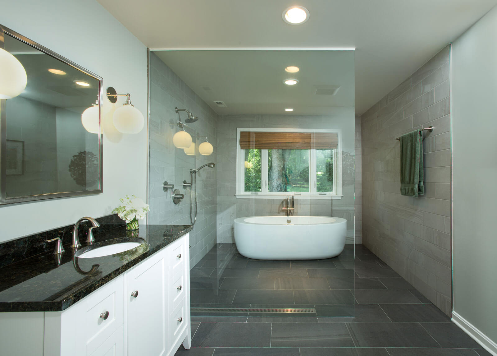 Frameless glass enclosure with a freestanding bathtub in a modern bathroom.