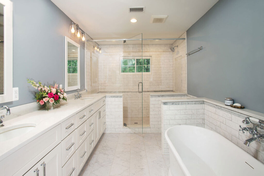 Bright bathroom with a frameless glass shower, marble counters and a soaking tub