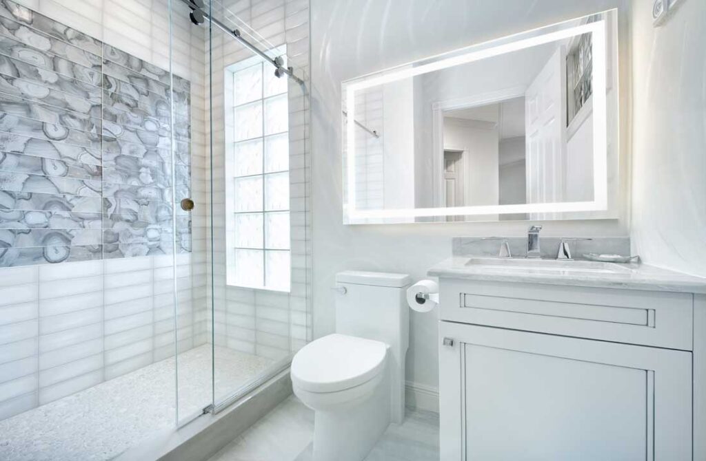 Bathroom with an LED backlit mirror and frameless glass shower